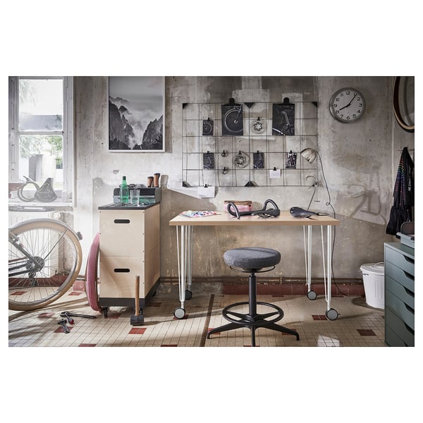 Industrial workspace with LINNMON desk, chair, decor, bike, tools, and clock.