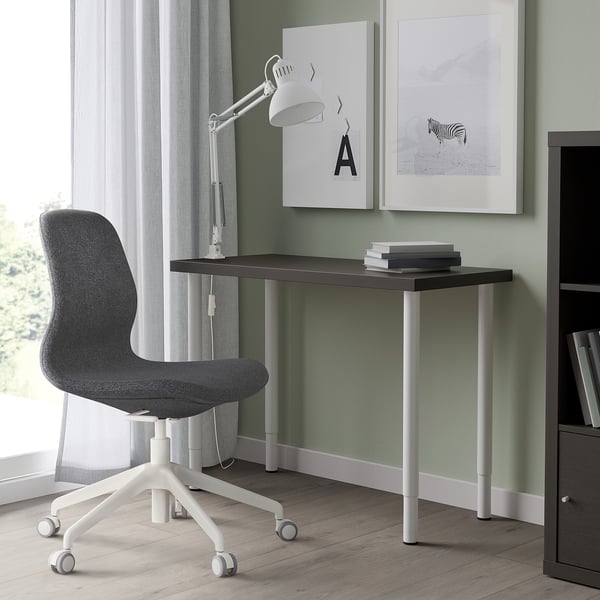 Modern black desk with grey chair, silver legs, zebra poster, lamp, storage.