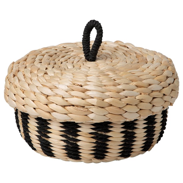 An IKEA MÄVINN woven basket with lid. Its beige with black accents, round, and handcrafted from banana fibres.