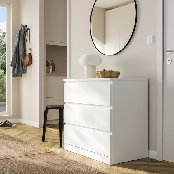 MALM white chest with lamp, mirror, and coats - minimalist entryway.