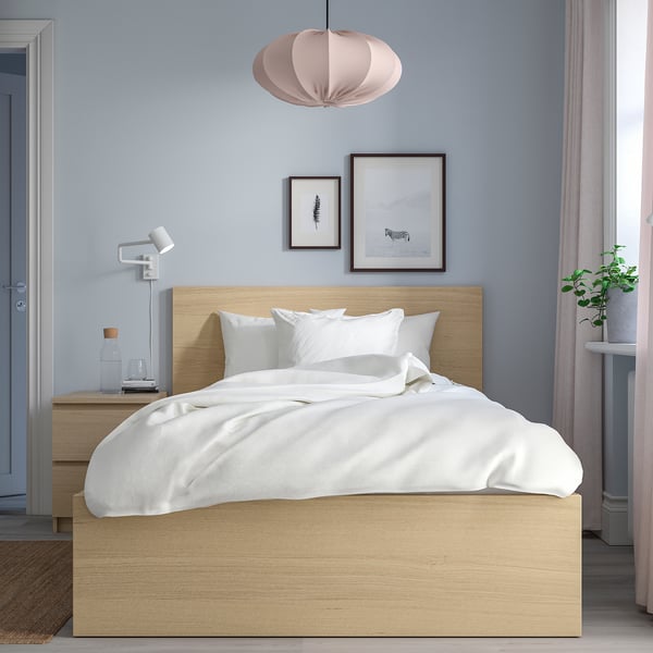 Modern light wood MALM bed. High headboard, white sheets. Room has pendant, wall art, plant.