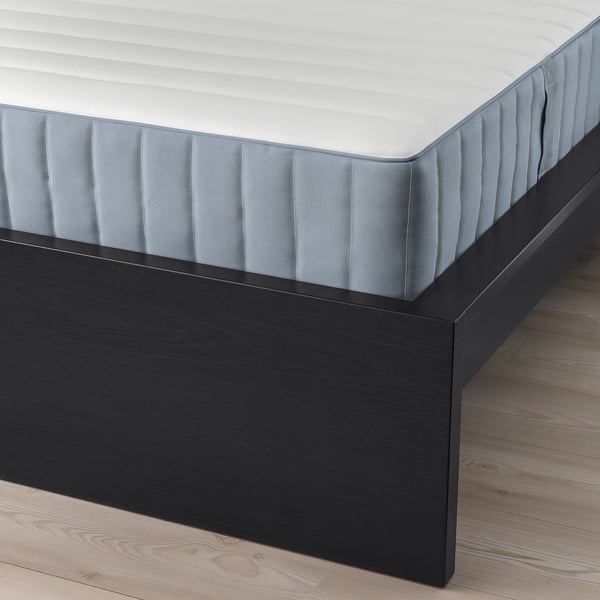 A modern black bed frame with a striped mattress resting on wooden slats, offering comfort and storage options.
