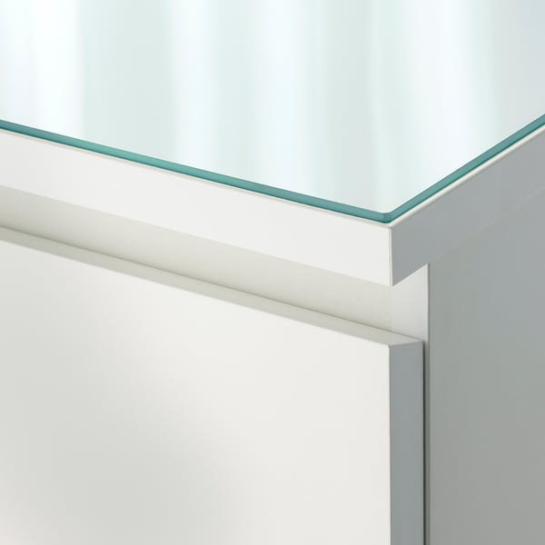 A close-up of a glass top corner. It a clear, smooth edge on a modern white surface.