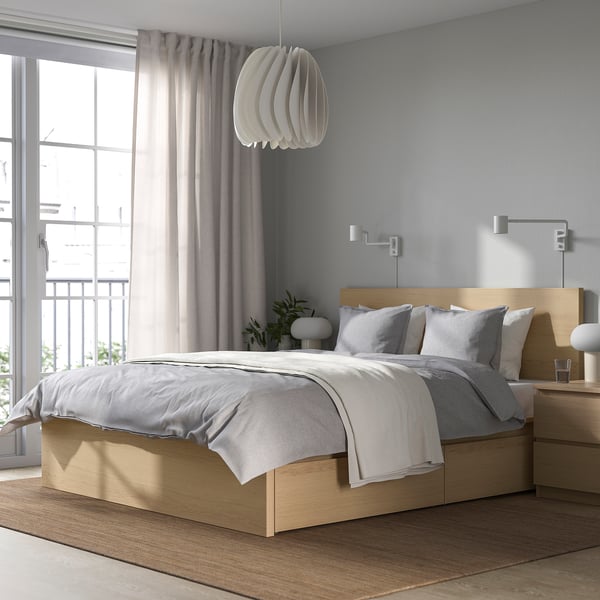 Bright, modern bedroom with a large, light wood MALM bed, grey linens, sleek bedside table, and large window with sheer curtains.