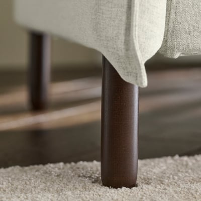 A close-up of a modern sofa leg, showcasing its sleek, dark wood finish and sturdy construction.