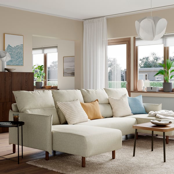Modern cream sectional sofa near windows with side tables and rug.