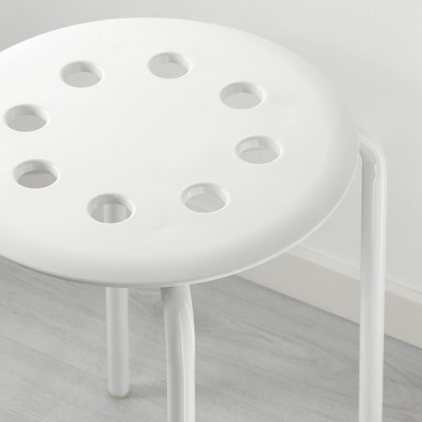 Small white stool with seven holes on circular seat, supported by three slim legs, showcasing quality craftsmanship and modern design.