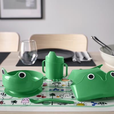 Green kids MATA set: bowl, cup, spoon, bib. Frog design, steady, bright plastic. Fits table, easy grips.