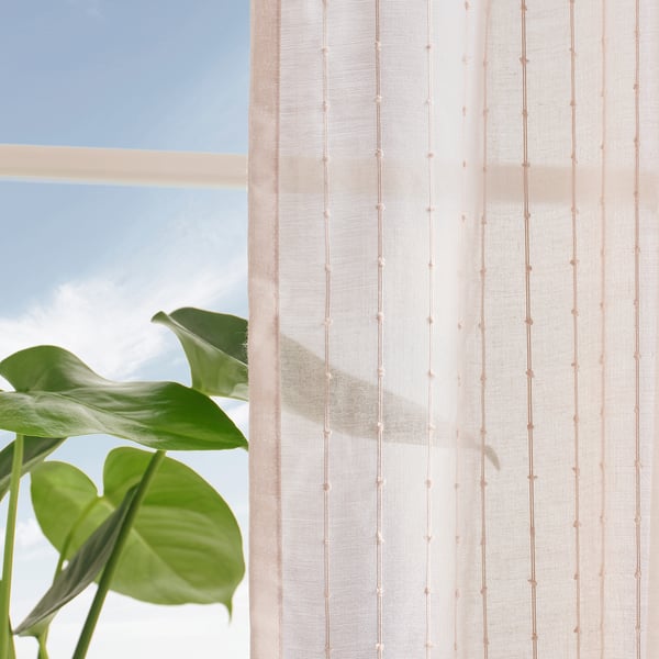 Pale pink striped curtains with stitching let light through, providing privacy and airiness, with a green plant.