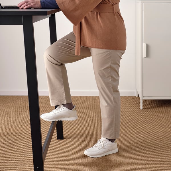 Person standing at high table using footrest, ideal for quick chats or work.