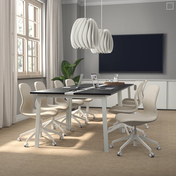 Modern conference room with MITTZON tables, flat screen tv, pendant light, white chairs, and natural light.