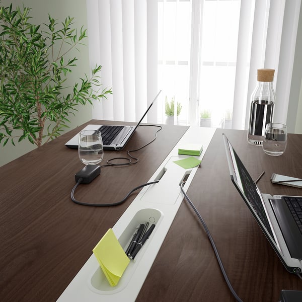 Modern conference table with power access, cable management, and supply compartments, ideal for meetings.