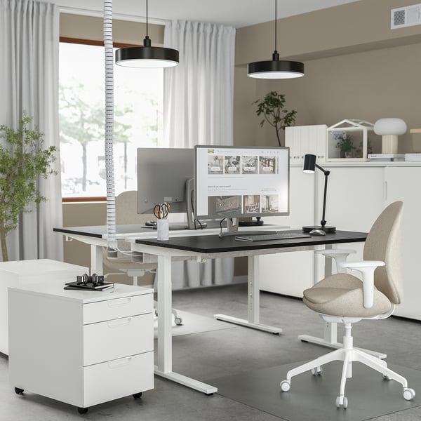 Modern height-adjustable home office desk with computer, chair, and storage.