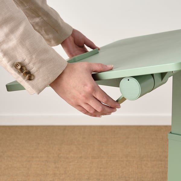 Person adjusting height of MITTZON laptop table. Gas spring mechanism shown.