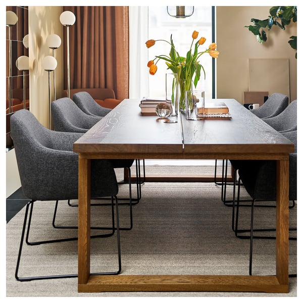 Modern dining set with grey chairs, wooden table, and orange flowers.
