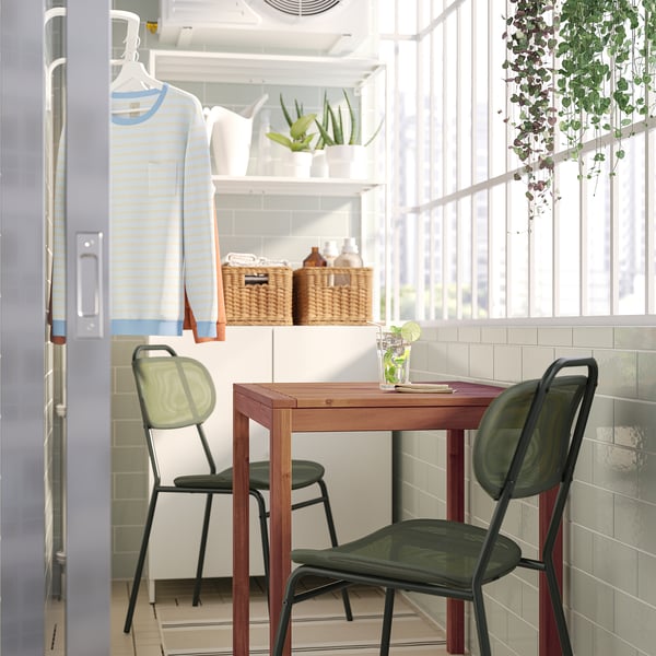 Modern dining set in cosy kitchen with green chairs and plants.