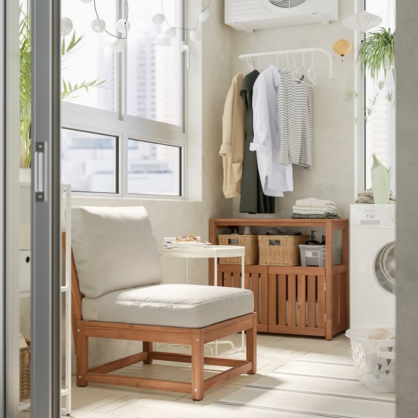 Modern laundry room with wooden NÄMMARÖ chair, white cushions, storage cabinet, clothes rack, washing machine, and plants.