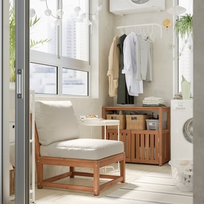 Modern laundry room with wooden NÄMMARÖ chair, white cushions, storage cabinet, clothes rack, washing machine, and plants.