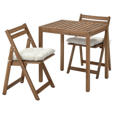 Small brown wooden patio set with table and two foldable chairs, featuring light-colored cushions. Suitable for outdoor use.