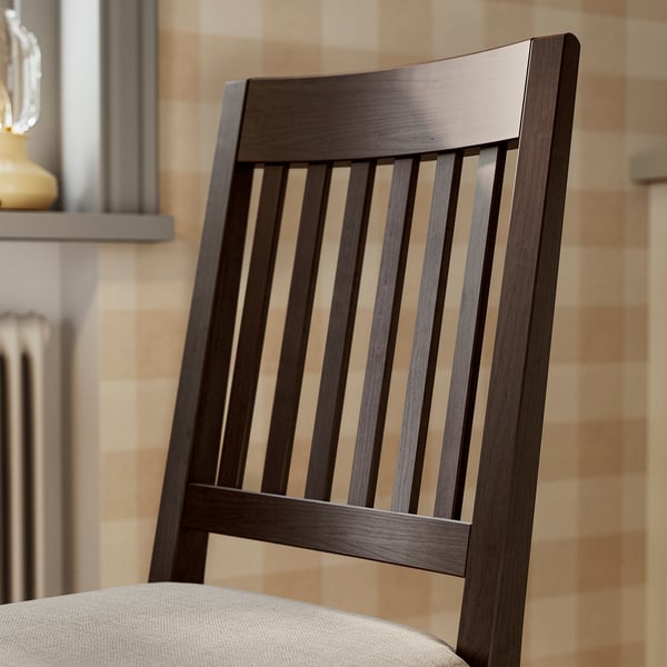 Dark wood chair with vertical slats, upholstered seat, set against patterned wall.