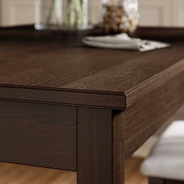 Well-crafted dark wood dining table with smooth, polished edge and visible grain texture, set in a cosy room.