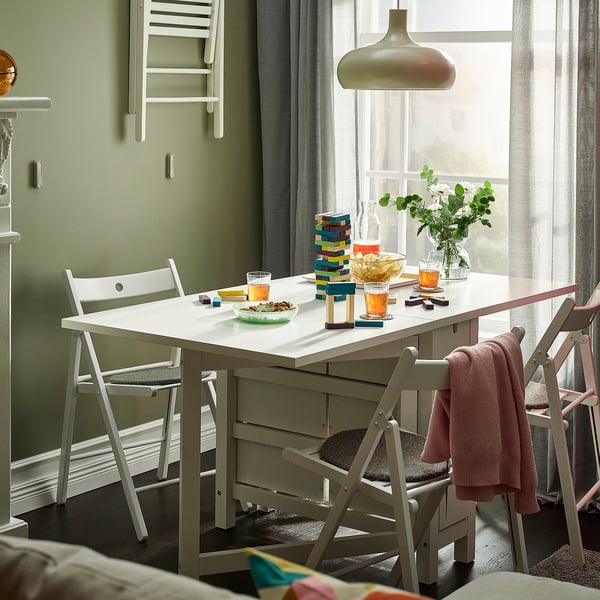 Modern dining set with NORDEN table & chairs, green walls, toy-filled window.