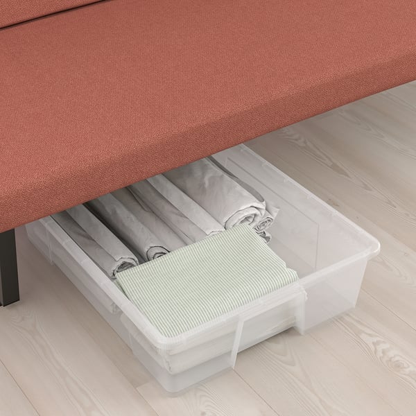 Storage bin under sofa with folded linens.