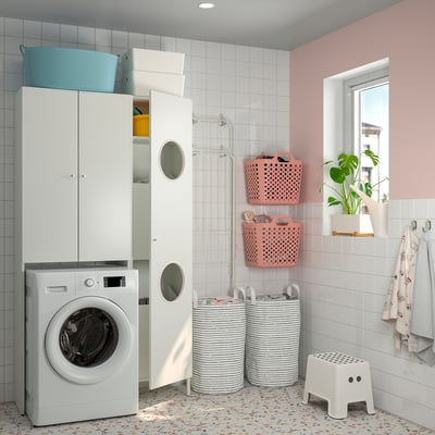 Modern white laundry room with NYSJÖN units, grey/pink baskets, washer, cabinets, and plants.