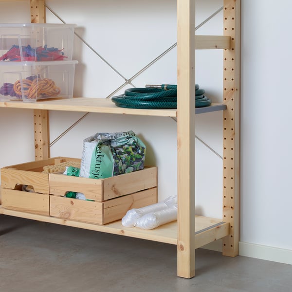 Wooden shelving unit with cross-brace support, storage crates, and garden hose.