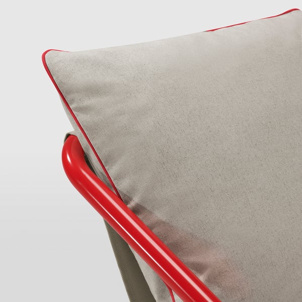 A modern cushioned chair with bold red legs. Light grey soft cushions, framed and bound in vibrant red. High-quality finish, cosy and stylish.