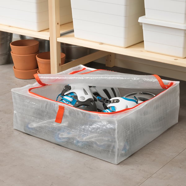 White PÄRKLA mesh storage bag with orange accents, holding helmets, on concrete floor.