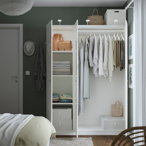 Neat white PAX wardrobe with folded clothes, hanging garments, and accessories. Good storage solution.