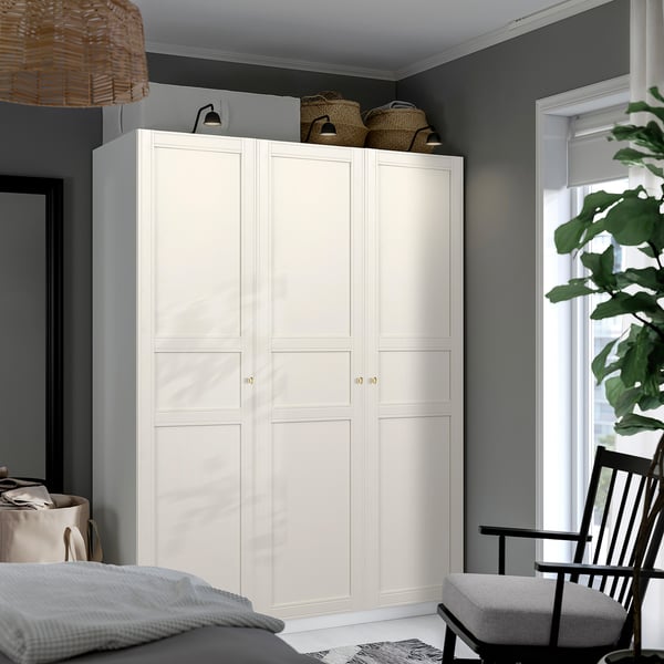 White PAX wardrobe with double doors, lighting, and woven decor.