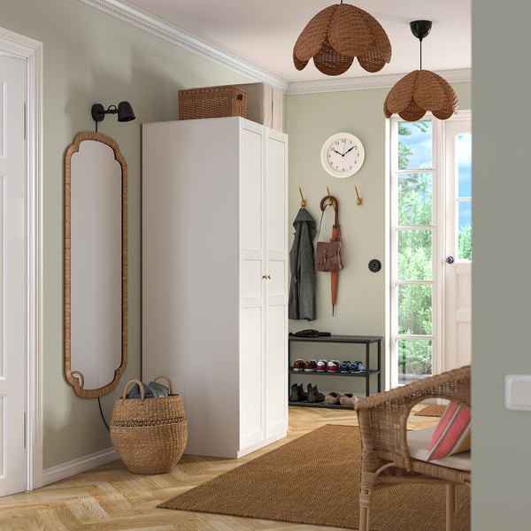 Well-organized entryway with a tall white PAX wardrobe, a large mirror, woven accessories, and a shoe rack.