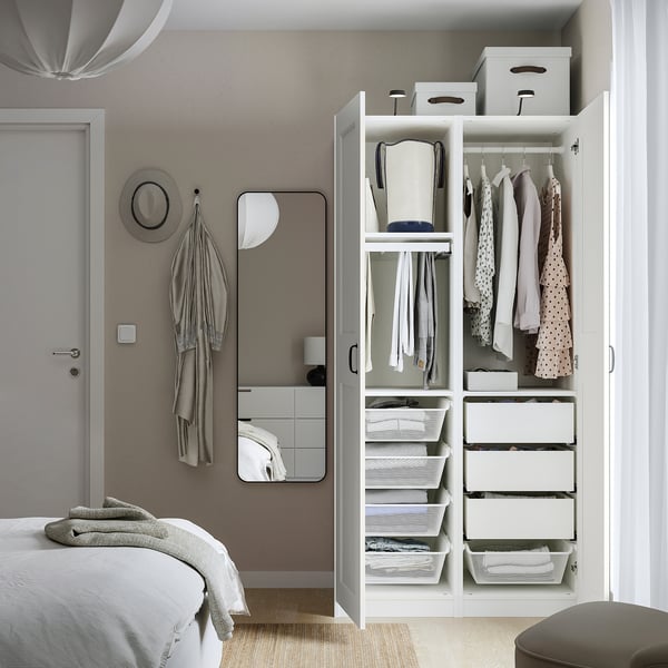 Modern bedroom with open wardrobe showing clothes, drawers, and storage.