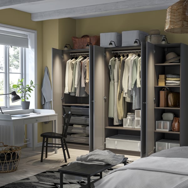 Modern bedroom with open wardrobes displaying clothes and storage. Desk, chair, natural light.