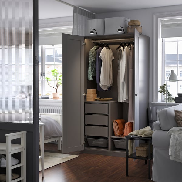 Open wardrobe with clothes, drawers, shelves, and a bench, ideal for organising a bedroom.