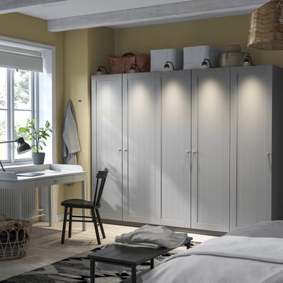 Minimalist bedroom with grey PAX wardrobe, black desk, and cosy bed.