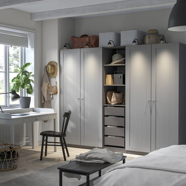 Modern bedroom with tall grey wardrobes, black desk, and hat stand.