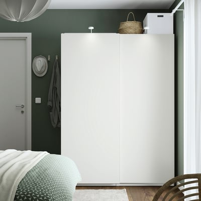 Modern bedroom with large white PAX wardrobe, green walls, and patterned bed.