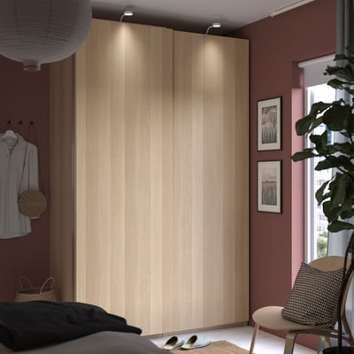 A cosy bedroom with a beige PAX wardrobe, a striped shirt, and a jute chair.