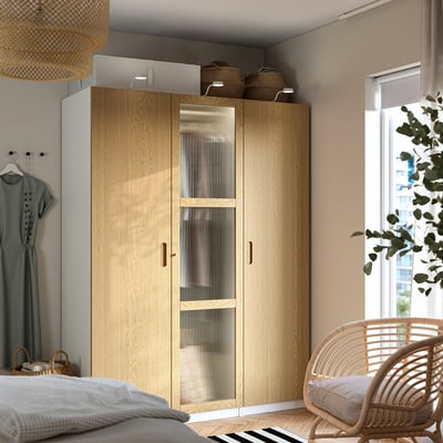 Wooden PAX wardrobe in organised bedroom with wicker chair, bed, mannequin.