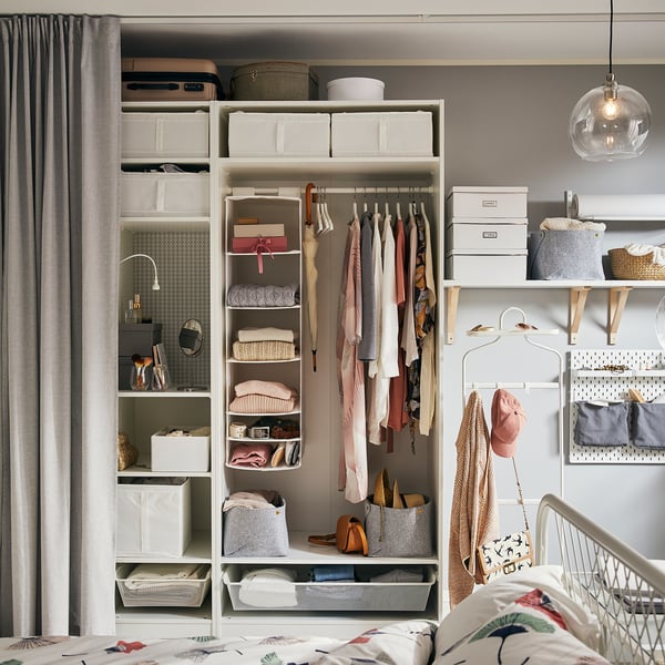 Neat bedroom closet with clothes, baskets, and accessories; hanging rack, shelves, and storage boxes.