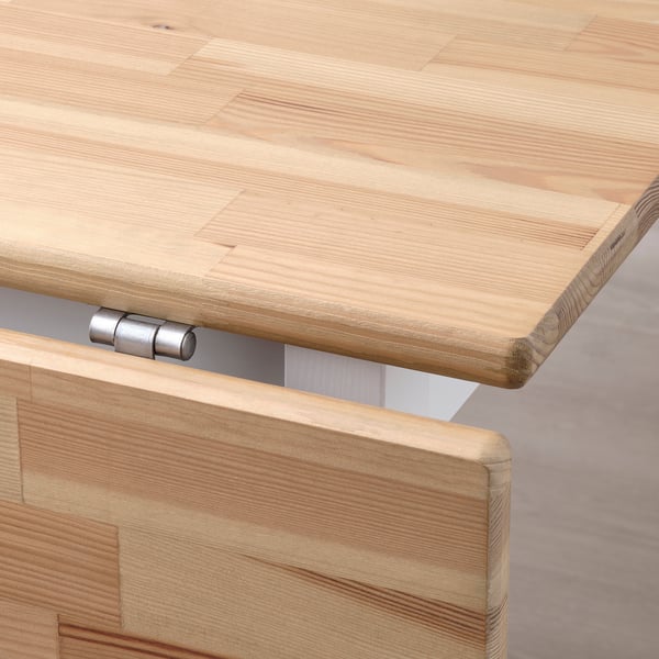 Close-up of well-crafted wooden table. Shows smooth, light-colored finish and sturdy metal hinge.