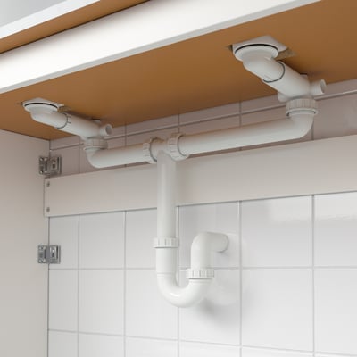 White pvc trap under brown cabinet in bathroom sink setup, with adjustable connexions and removable drain for easy cleaning.