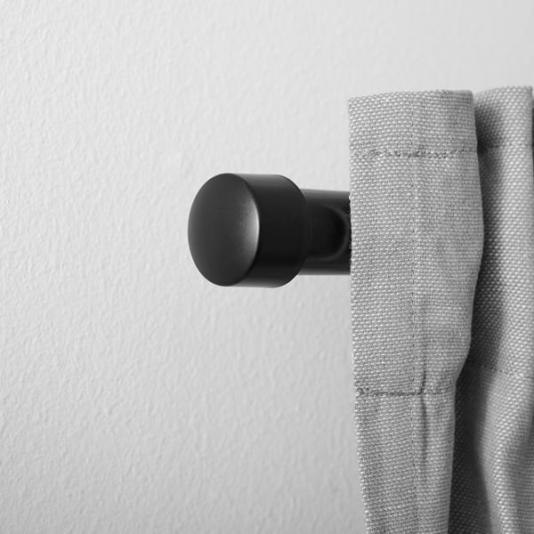 Black finial on curtain rod; decorates and holds curtains.