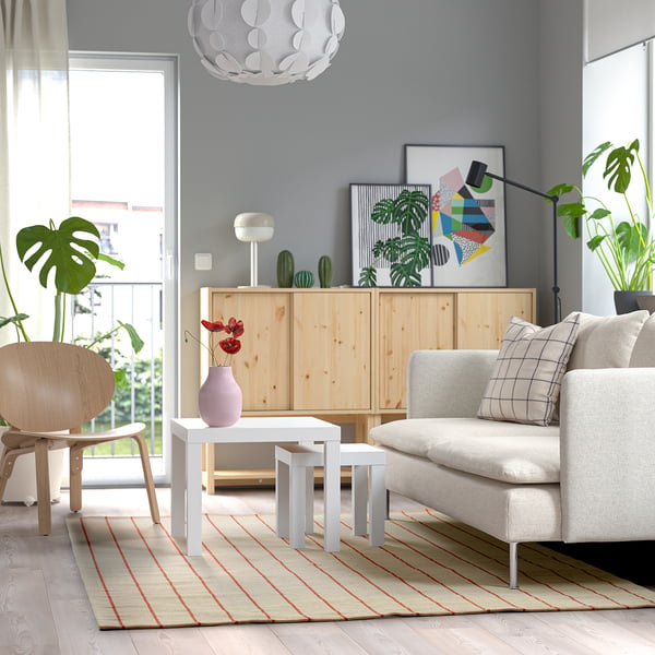 Modern living room with grey sofa, white coffee table, wooden chair, and soft cotton off-white rug with red stripes.