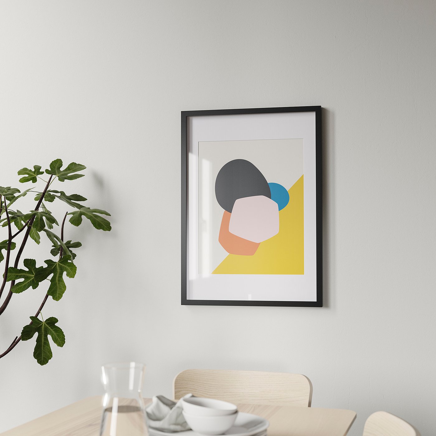 Abstract art print in black frame on grey wall, dining table with white dishes, green plant.
