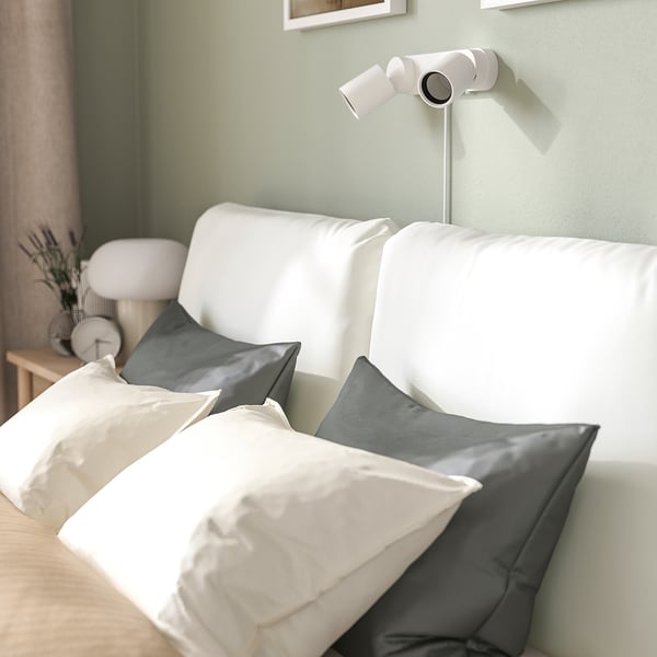 A modern bed with a sloped headboard and large pillows, perfect for sitting and reading.