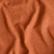 Close-up of texture of burnt orange fabric, displaying smooth quality.